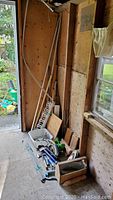 Photo showing a collection of tools including rebar, pump, wire, chain, toolbox in a shed area