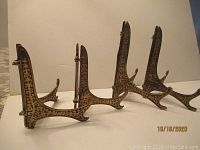 Four carved dark wood ornate photo or plate display stands showing scroll patterns and curved legs