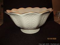 Large white Lenox bowl with gold-trimmed scalloped edge and embossed leaf pattern on black background