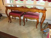 Sofa table with two matching upholstered stools sitting underneath, showing front view of entire set and carved detail on table apron.