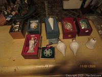 Group of various Lenox and other holiday ornaments on a wooden table, some in original boxes.