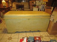 Yellow painted vintage hope chest closed, showing overall exterior with wear signs
