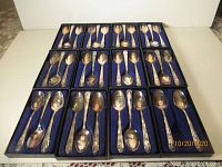 Overview of all 35 collectible spoons displayed in black presentation boxes with blue felt lining.