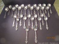 Photo of 25 spoons showing detailed classical ornate Georgian pattern handles and silver finish.
