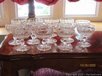 Clear Waterford crystal footed dessert bowls displayed on a wooden surface, showing 13 bowls arranged in a group, some with visible intricate cut glass patterns.