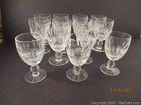 Front group view of thirteen crystal glasses with visible cut design, arranged in rows.