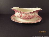 Gravy boat with cranberry floral pattern on ivory base on black background