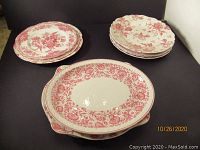 Photo of three stacks of cranberry and ivory plates showing floral patterns with different border designs.