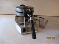 Front angled view of the Waring Pro waffle maker showing handle, power dial, and model plate.