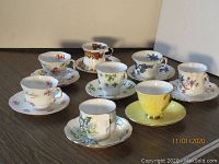 Photo showing all 8 collectible cups and saucers with varied floral and tartan patterns, mostly bone china with gold trim.