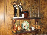 Overview of wood shelves with bar ware and decorations including Liquore Galliano decanters, decorative plate, pitchers, and other vintage bar collecting items
