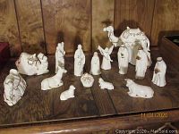15-piece cream and gold ceramic nativity set displayed on wood surface showing figures including Mary, Joseph, baby Jesus, camels, shepherds, and animals