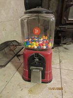 Front view showing the glass globe filled with multi-colored gumballs, red base and decal indicating 1 cent price.