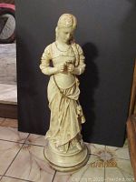 Full view of the 24-inch tall Alexander Backer Co. chalkware statue of a young woman with braided hair in period dress on a round base.