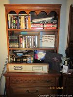 Wooden shelving unit containing an assortment of collectible VHS tapes including Star Wars, Star Trek, and others; display box for Captain Marvel color posters and t-shirts box for Star Trek tee shirts
