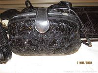 Black beaded clutch with flap and zipper closure displaying floral pattern made of beads