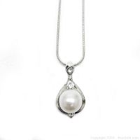Front view of the silver necklace pendant with a white pearl and clear stones.
