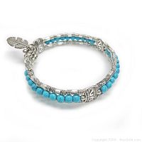 Bracelet showing turquoise beads and detailed Tibetan silver elements with feather charm close-up.