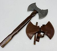 Full view of double-headed axe and detached leather sheath pieces laid flat