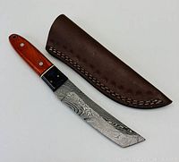 Full view of the knife and leather sheath, showing the stained wood handle and Damascus blade with intricate patterns.