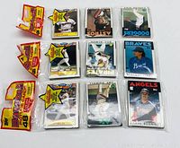 Three unopened 1986 Topps baseball card packs shown with individual cards visible beneath each pack, including stars like Cecil Fielder and Tony Gwynn. Packs remain sealed in original 1986 packaging.