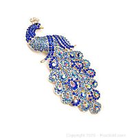 Front view of large dark blue bejeweled peacock brooch with dark blue, light blue, and iridescent rhinestones on gold-tone metal.