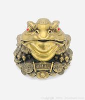 Front view of the Jin Chan money toad statue with visible red eyes and coin details.