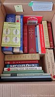Box packed with various genealogy and surname related books, showing spines and titles such as 'Discovering Surnames', 'Scottish Surnames', and others.