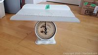 Full view of vintage white metal baby scale showing the entire scale including weighing platform and dial.