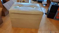 Front, side view showing cream vinyl exterior and cushioned top with button tufting.