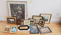 Overview of the collection showing multiple framed pictures and prints arranged on a floor against a wall, ranging in size and style.