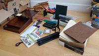Lot of wooden letter writing box, small wooden wagon, pens, coloring leads, money counter, hole punch, bookmarks, leather folder, silk bags, file folders, clipboard, file organizer, picture stands, and wall art on floor