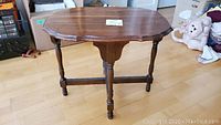 Full view of wooden end table showing scalloped oval top and turned legs with stretcher supports
