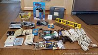 Wide angle photo showing entire lot of tools, hardware and electrical items laid out on floor.