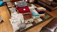 Overview of all linens including pillows, blankets, comforter, towels, tablecloth, and bed skirt arranged on floor