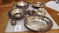 Full view of all seven silverplated items including trays, bowls, candle holders, and glass shade.