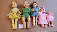 Five dolls in a row showing variety in size, clothing, and material