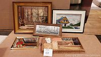 Five framed art pieces including a large ship painting, a mirror sign, two scenic paintings, and a wooden tray with beads.