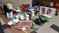 Wide view of assorted kitchenware including ceramic dishes, mugs, glassware, cookie jar, and decorative items.