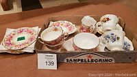 Top and side view of Serena patterned plates, cups, and additional cups with different floral design in a box