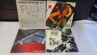 Front covers of four Alice Cooper vinyl albums displayed on a white surface showing titles Flush the Fashion, Special Forces, Lace and Whiskey and Alice Cooper's self-titled album.