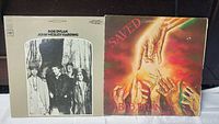 Front view of two Bob Dylan vinyl albums: John Wesley Harding on left, Saved on right, showing cover artwork and overall condition.