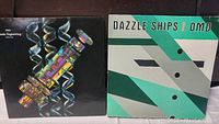 Front covers of the two vinyl records: 'Genetic Engineering' and 'Dazzle Ships' by OMD