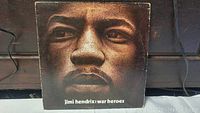 Front cover of Jimi Hendrix War Heroes vinyl record album featuring a large close-up image of Jimi Hendrix's face with album title text below.