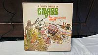 Front cover of the vinyl album "A Child's Garden of Grass: A Pre-Legalization Comedy" featuring psychedelic and marijuana-themed art and objects.