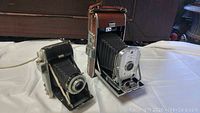Front view of Kodak Tourist and Polaroid Land Camera Model 95b side by side on table