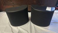 Front view of two black Energy Reference Connoisseur RC R B1 speakers with fabric covers and curved edges.