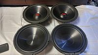 Four 12 inch woofers in black front cone view showing design and size