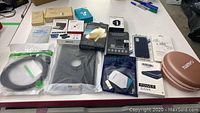 Overview of lot contents showing power bank, phone cases, cables, headphones case, and screen protectors