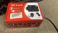 Photo of the RV lock product box showing the brand and product features including remote control and manual control with double lock tongue design.